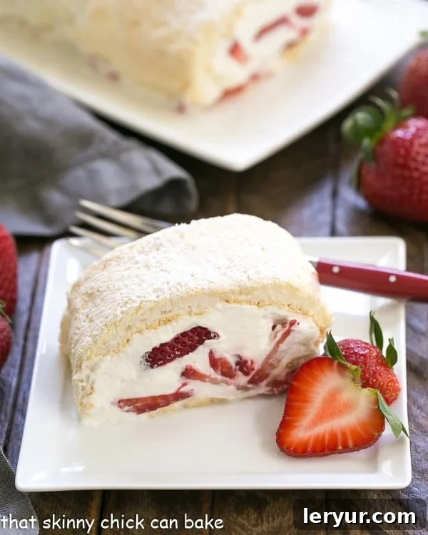 Strawberry Filled Meringue Roulade slilce on a square white plate with a red handled fork and strawberry garnish