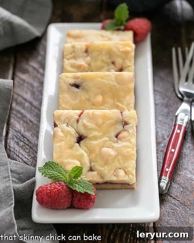 Decadent White Chocolate Raspberry Delight 4 White Chocolate Raspberry Bars lined up on a rectangular white tray.