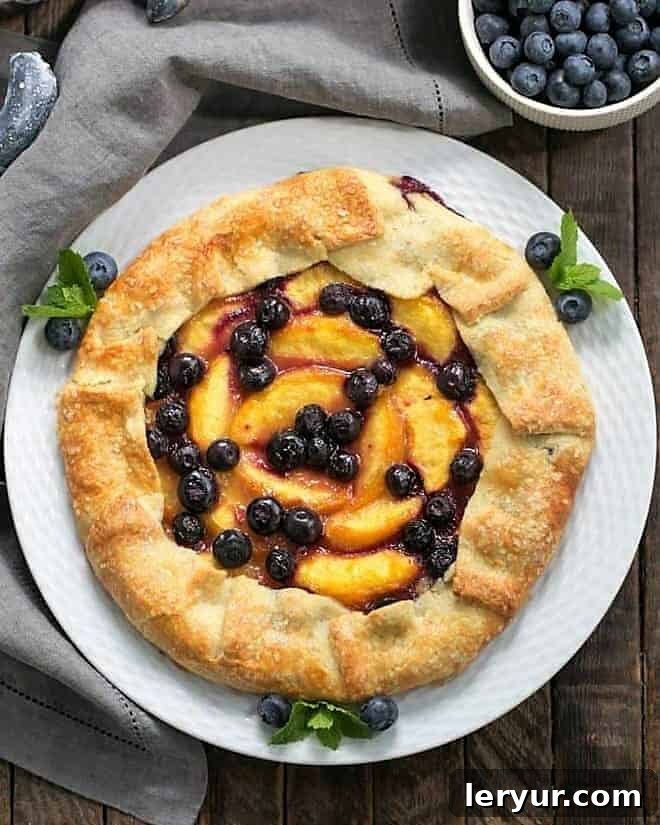 Sun-Kissed Peach and Blueberry Pastry 2 An inviting overhead view of a freshly baked Peach Blueberry Galette, showcasing its golden crust and vibrant fruit filling, presented on a white serving plate.