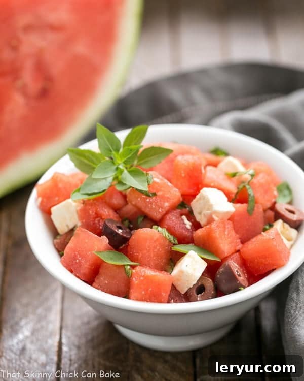 Watermelon Feta Basil Salad with Balsamic Vinaigrette - An unusual, refreshing and irresistible summer side dish! Watermelon Feta Basil Salad with Balsamic Vinaigrette in a white bowl, garnished with fresh basil leaves.