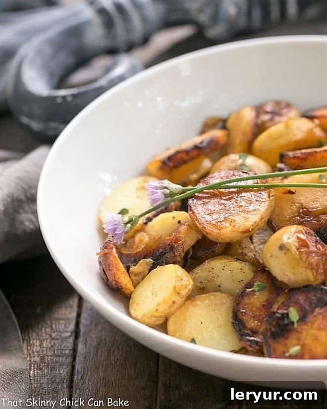 Grilled Potato Packets with Shallots and Thyme in a white serving bowl garnished with chive blossoms
