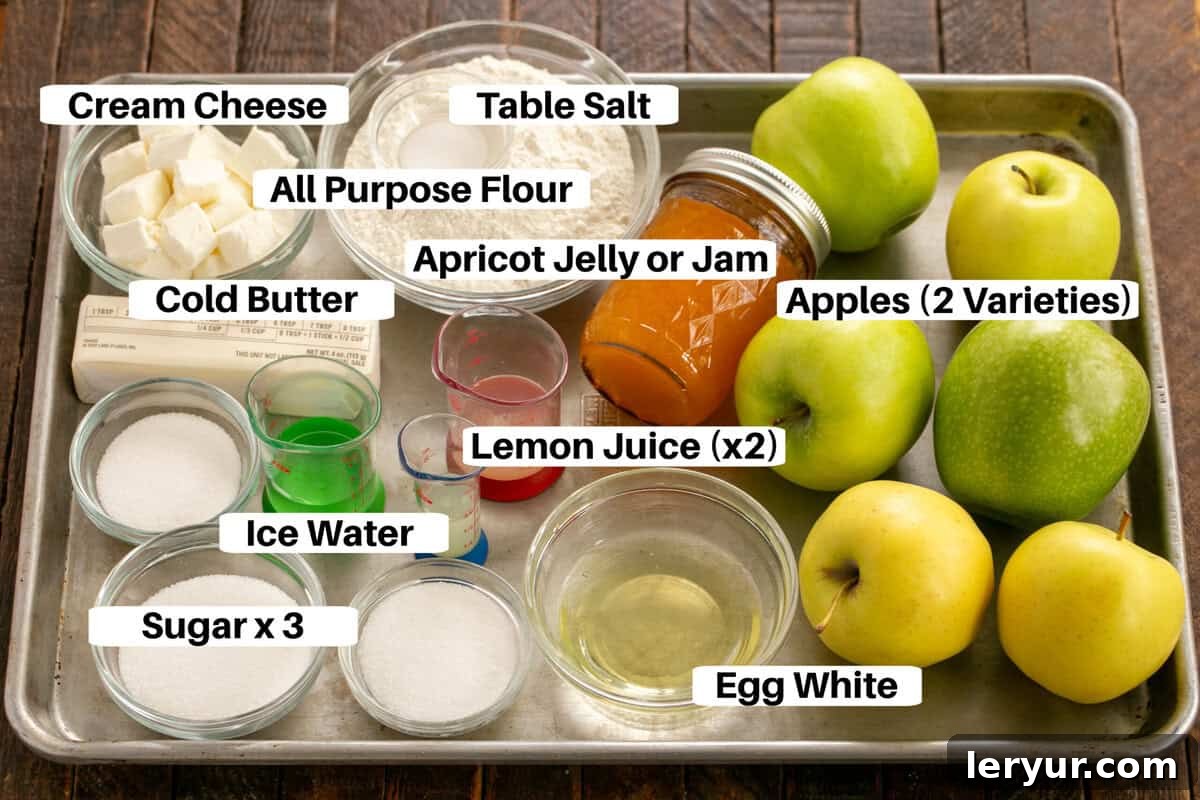 Various ingredients for an Apple Galette, including apples, flour, butter, and cream cheese, neatly arranged on a metal sheetpan with labels.