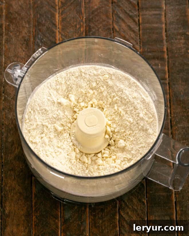 Galette crust ingredients, including flour, sugar, butter, and cream cheese, in a food processor, ready to be pulsed.