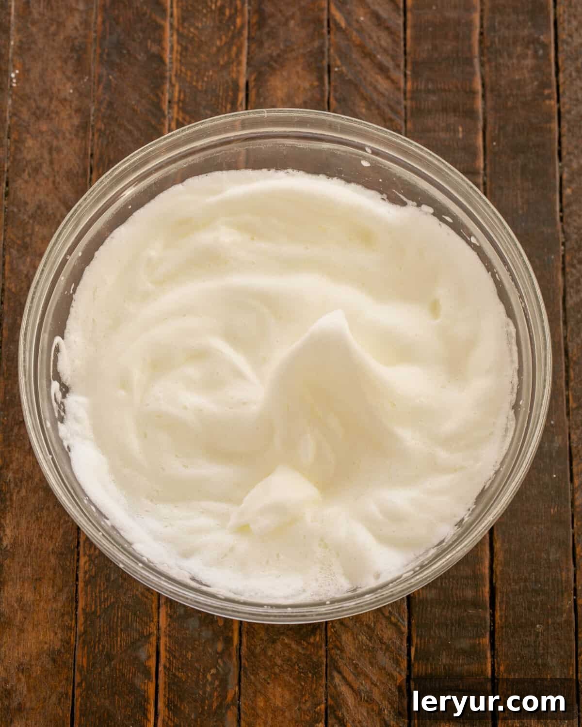 A bowl of egg whites being whipped, showing a satiny, frothy texture.