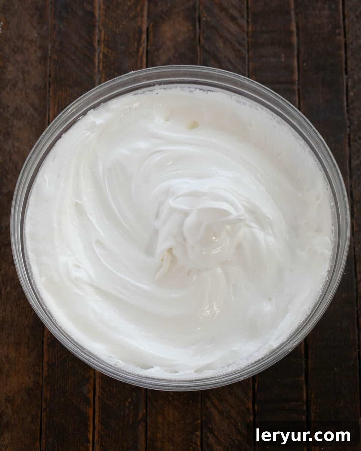 Egg whites beaten with superfine sugar, forming stiff, glossy peaks in a mixing bowl.
