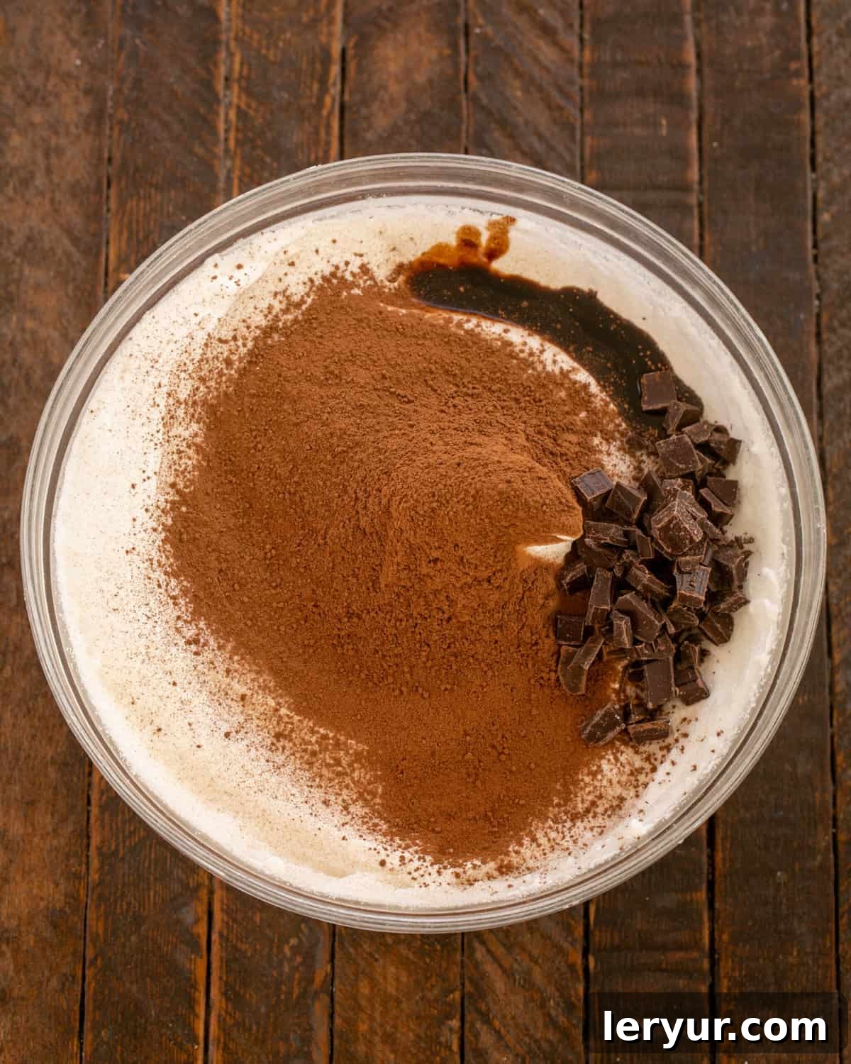 Cocoa powder, chopped chocolate, and balsamic vinegar being gently folded into the stiff egg whites.