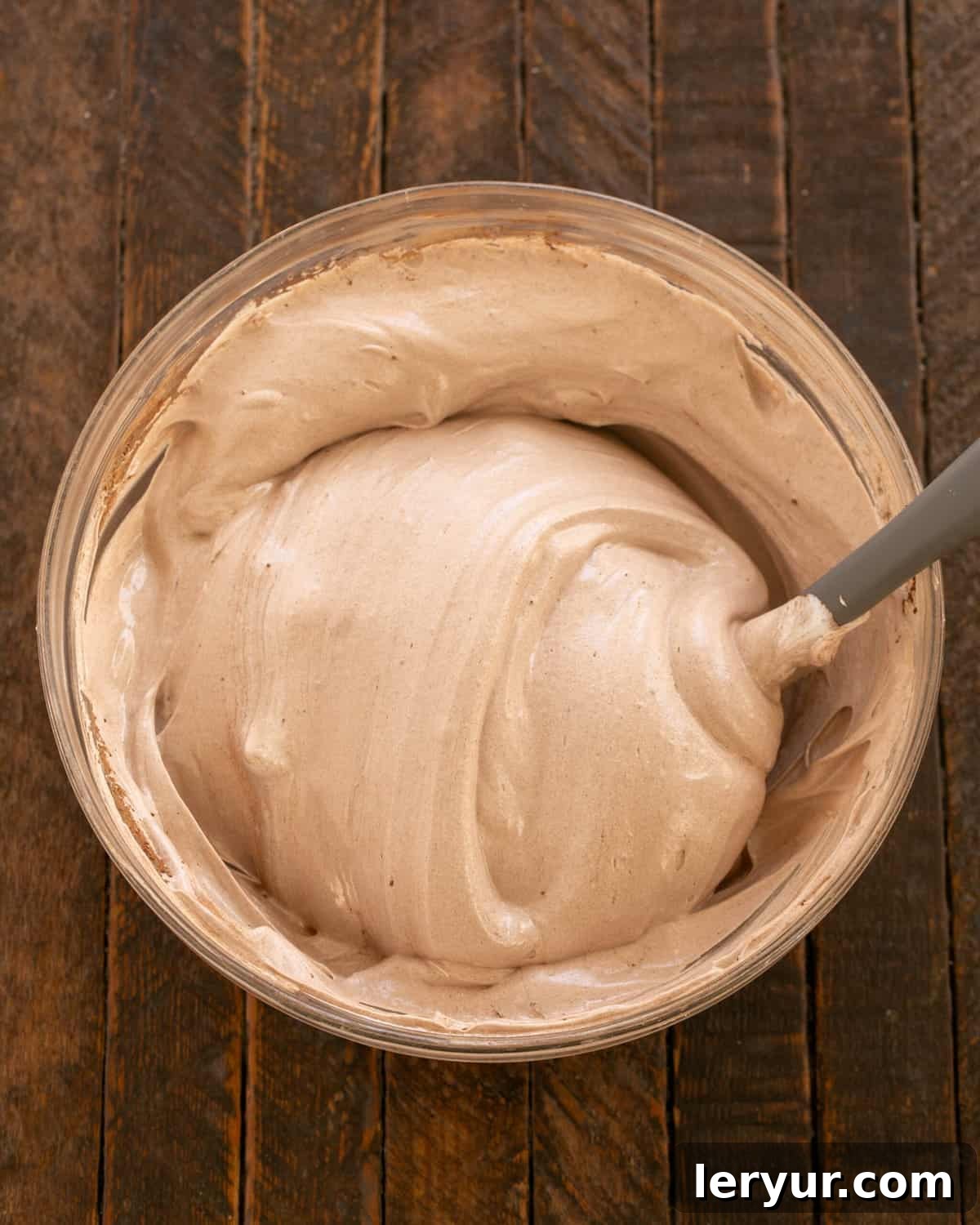 Chocolate meringue mixture spread into a circular shape on parchment paper with a well in the center.