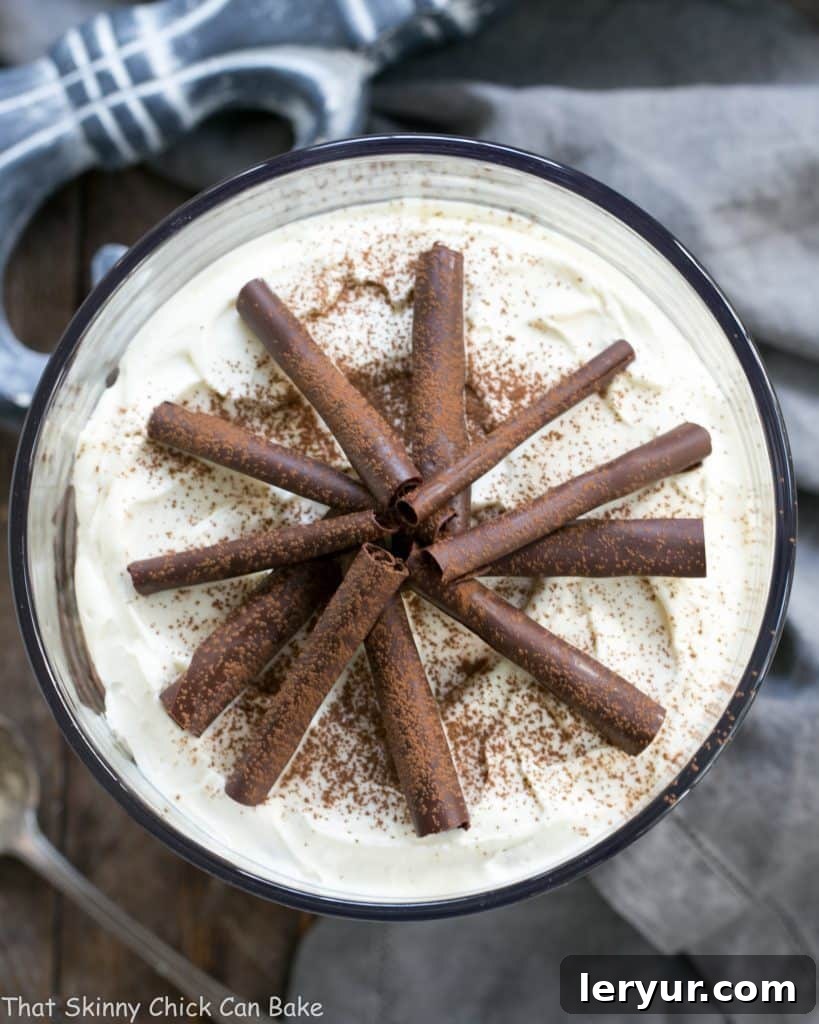 An overhead shot showcasing the intricate layers of the Fudgy Brownie Trifle with Chocolate Mousse, adorned with a generous sprinkle of chocolate curls and cocoa powder. The rich colors of the layers create an inviting visual.