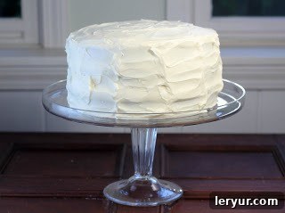 A red velvet cake on a glass stand in front of a window