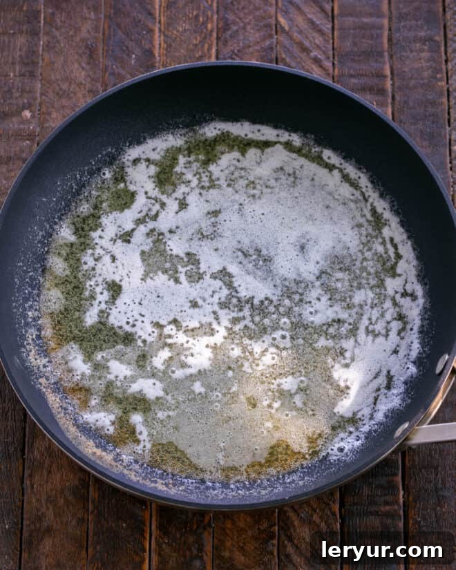 Melted butter in a large skillet, ready for the next ingredients.