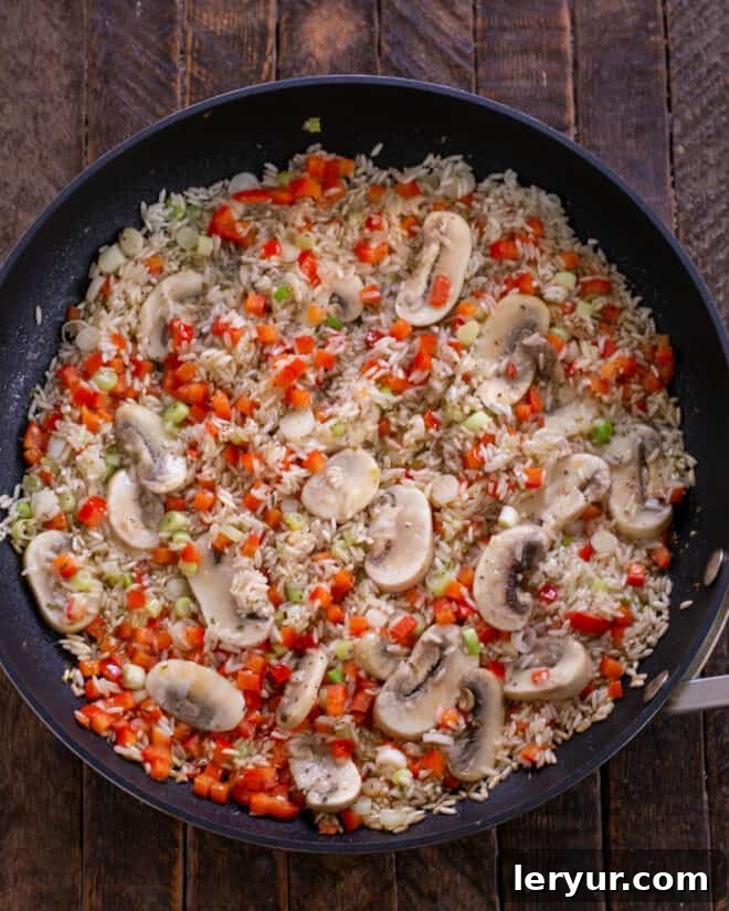 Mushroom and rice mixture cooking in a skillet until mushrooms are tender.