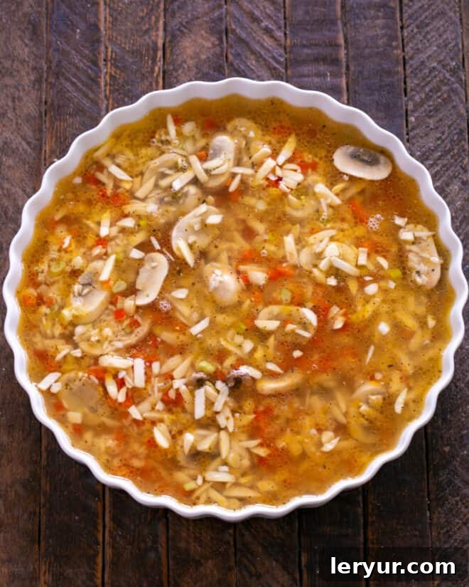 Chicken broth being added to the baking dish with the rice mixture.