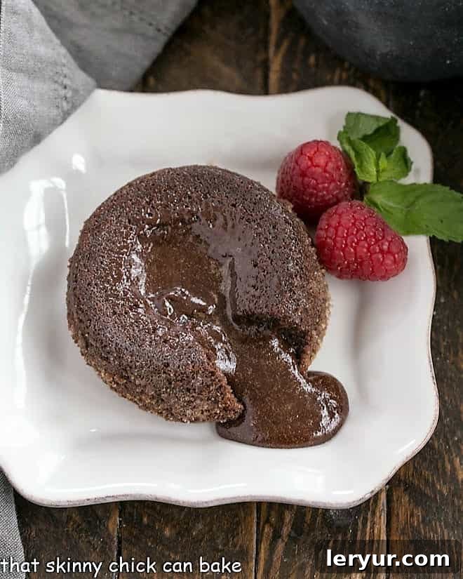 A perfectly baked molten lava cake with a forkful of cake revealing its rich, fudgy interior, served on a pristine white plate.