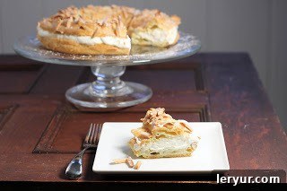 A perfectly sliced Paris-Brest revealing its delicate layers of choux pastry and creamy filling on a white plate