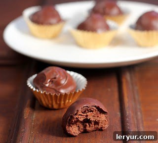 Homemade chocolate truffle with a bite removed, alongside other whole truffles