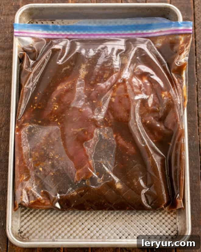 Flank steak submerged in the red wine, soy, and balsamic marinade in a Ziploc bag.