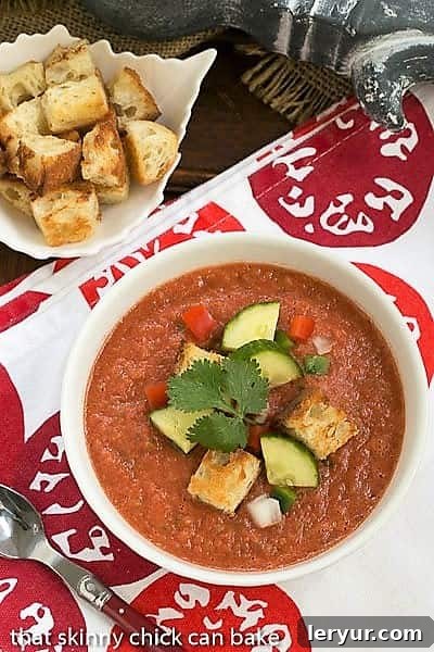 Recipe for Gazpacho with Homemade Croutons - A chilled Spanish tomato soup topped with diced vegetables and homemade croutons Overhead view of Classic Gazpacho with Homemade Croutons in a white bowl topped with cucumbers, peppers and croutons.