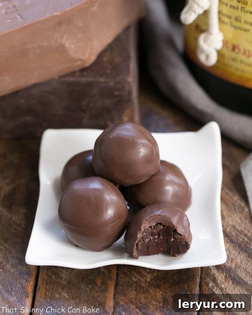 Chocolate Frangelico Truffles - Exquisite truffles flavored with hazelnut liqueur plus a guide for tempering chocolate Chocolate Frangelico Truffles arranged neatly on a square white ceramic plate, showcasing their smooth, tempered coating.