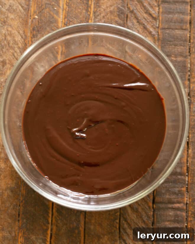 Melted chocolate mixture being stirred until perfectly smooth and glossy.