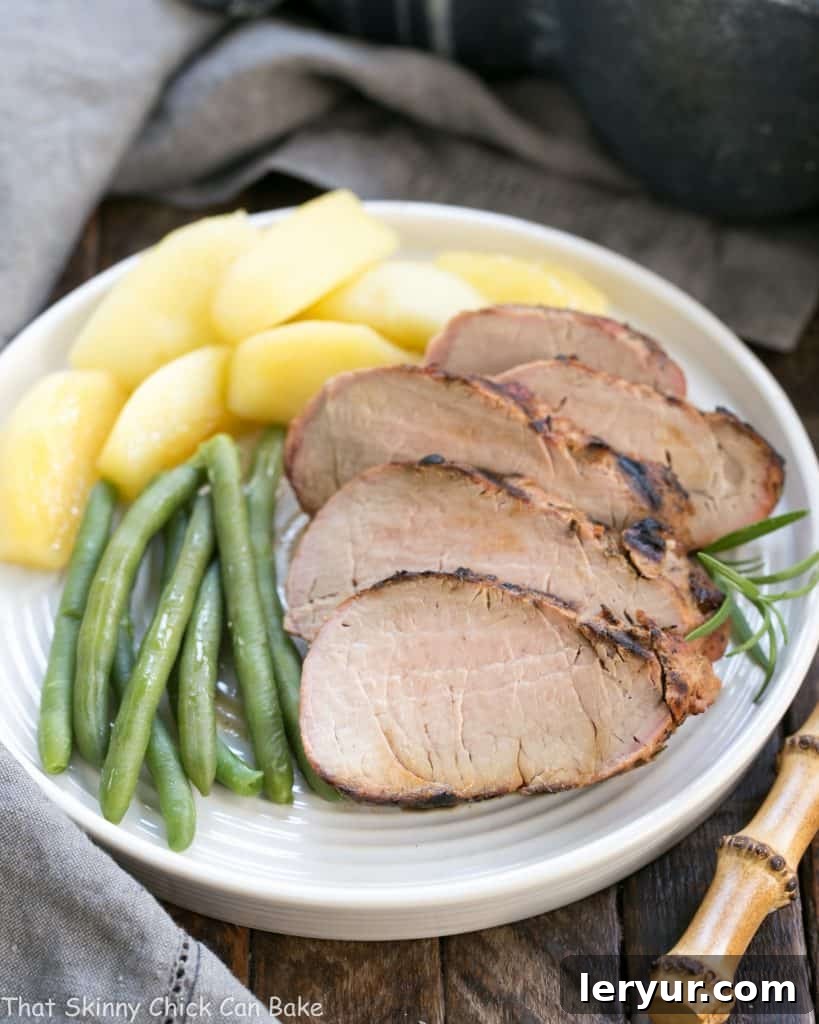 Grilled Maple-Glazed Pork Tenderloin 8 Succulent Maple Grilled Pork Tenderloin slices arranged beautifully on a white plate, accompanied by vibrant green beans and sweet sautéed apples, ready to be enjoyed.