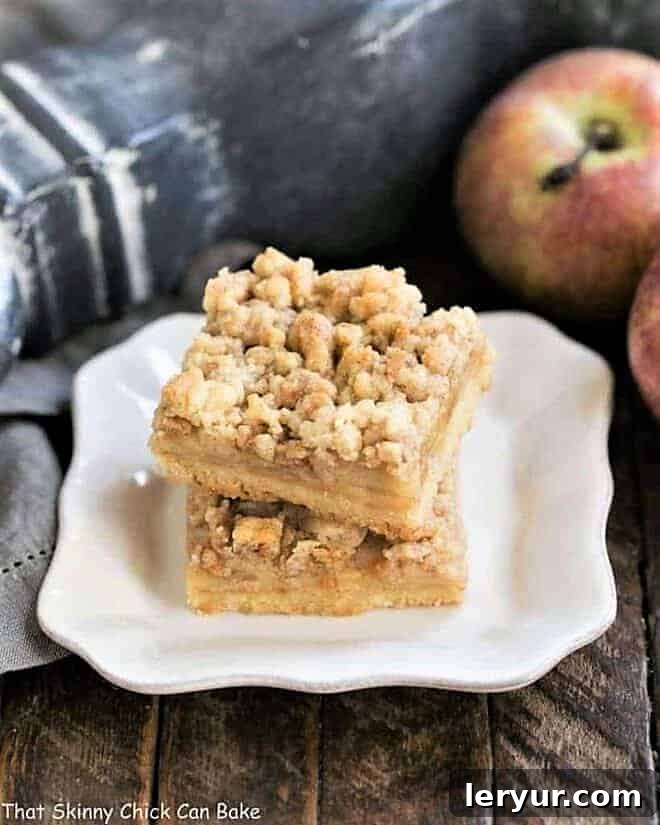 Caramel Apple Pie Toffee Bars stacked on a white plate, showcasing layers of shortbread, apple, and streusel.