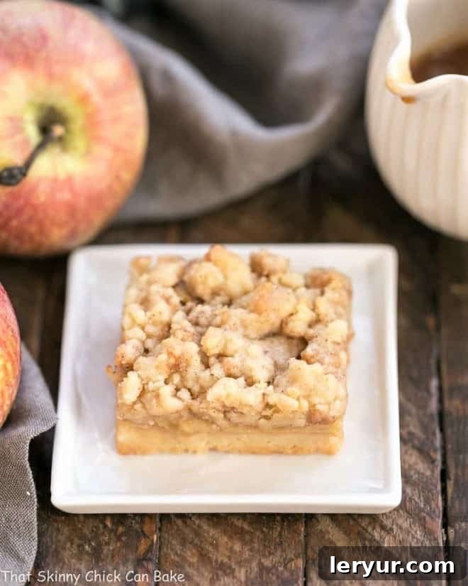 A single Caramel Apple Pie Toffee Bar on a square plate, showcasing its golden streusel and tender apple filling.