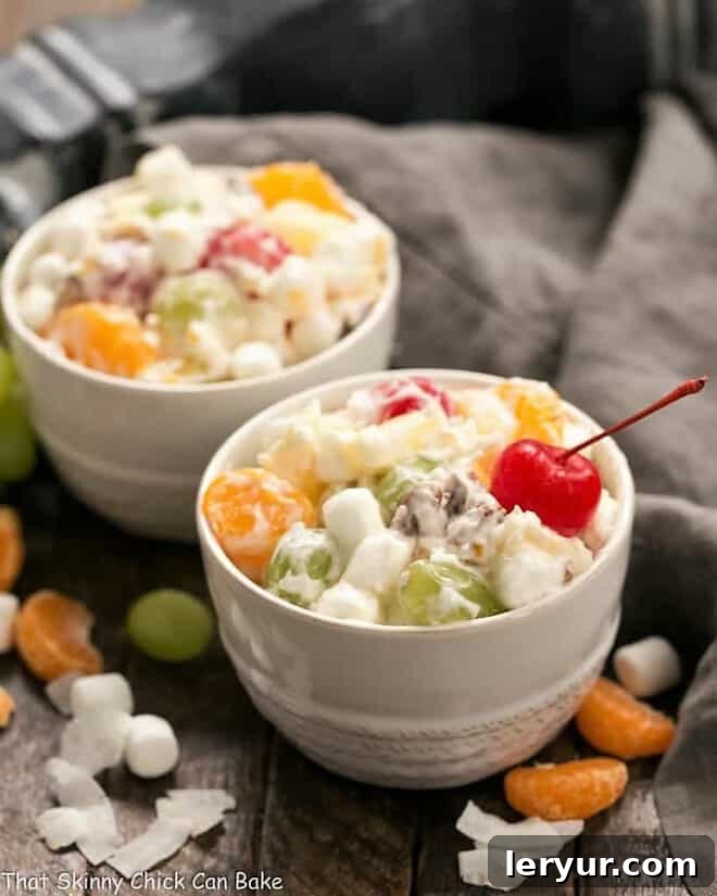 Two small white bowls brimming with The Best Ambrosia Salad {No Cool Whip}, showcasing its fluffy texture and colorful fruit.