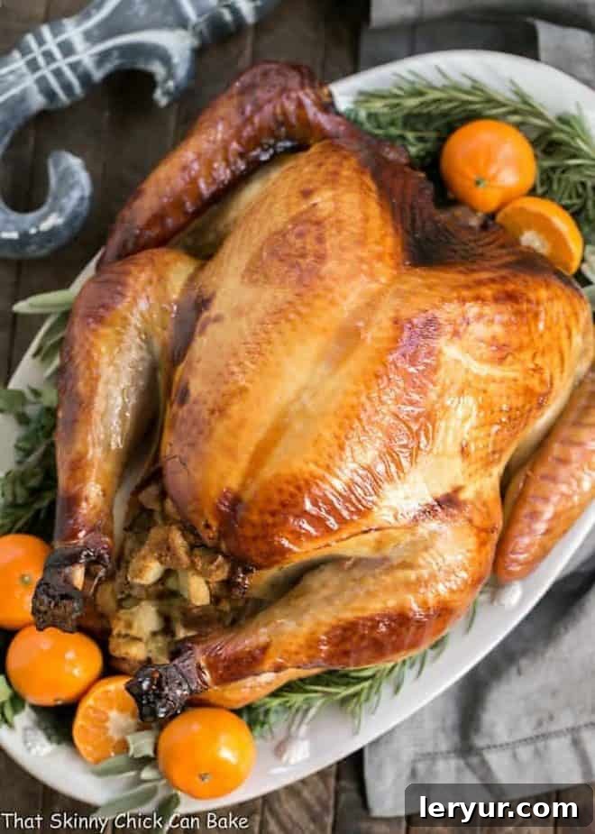 Sweet and Savory Holiday Brined Turkey 2 A perfectly cooked Honey Brined Turkey, adorned with fresh herbs and orange slices, presented on a white platter for a festive spread.