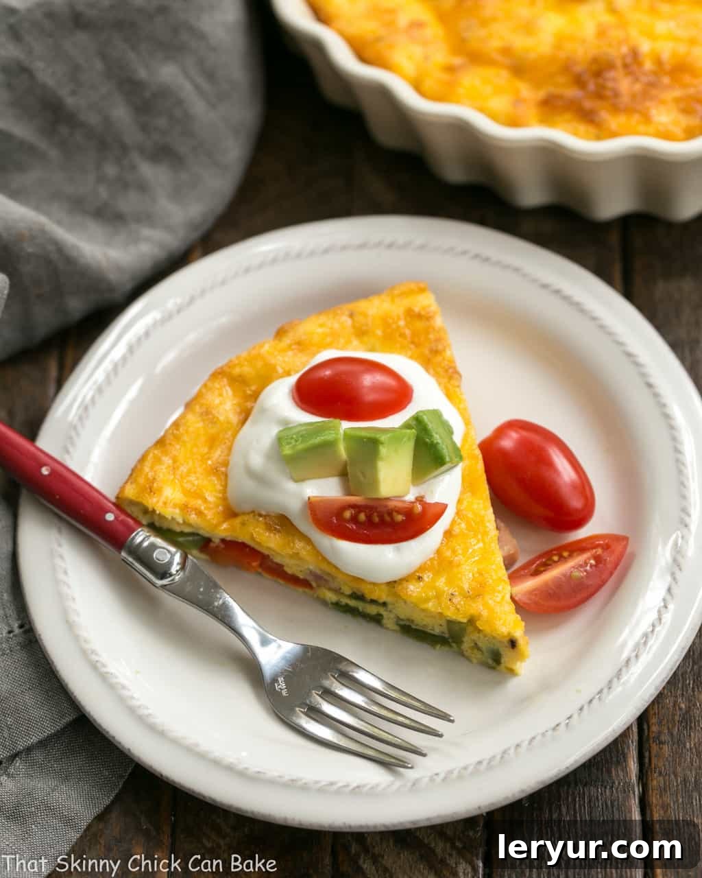 Baked Denver Omelet - A simple, scrumptious, easy to make baked ham and vegetable omelet! Baked Denver Omelet slice on a white plate with a red handled fork.
