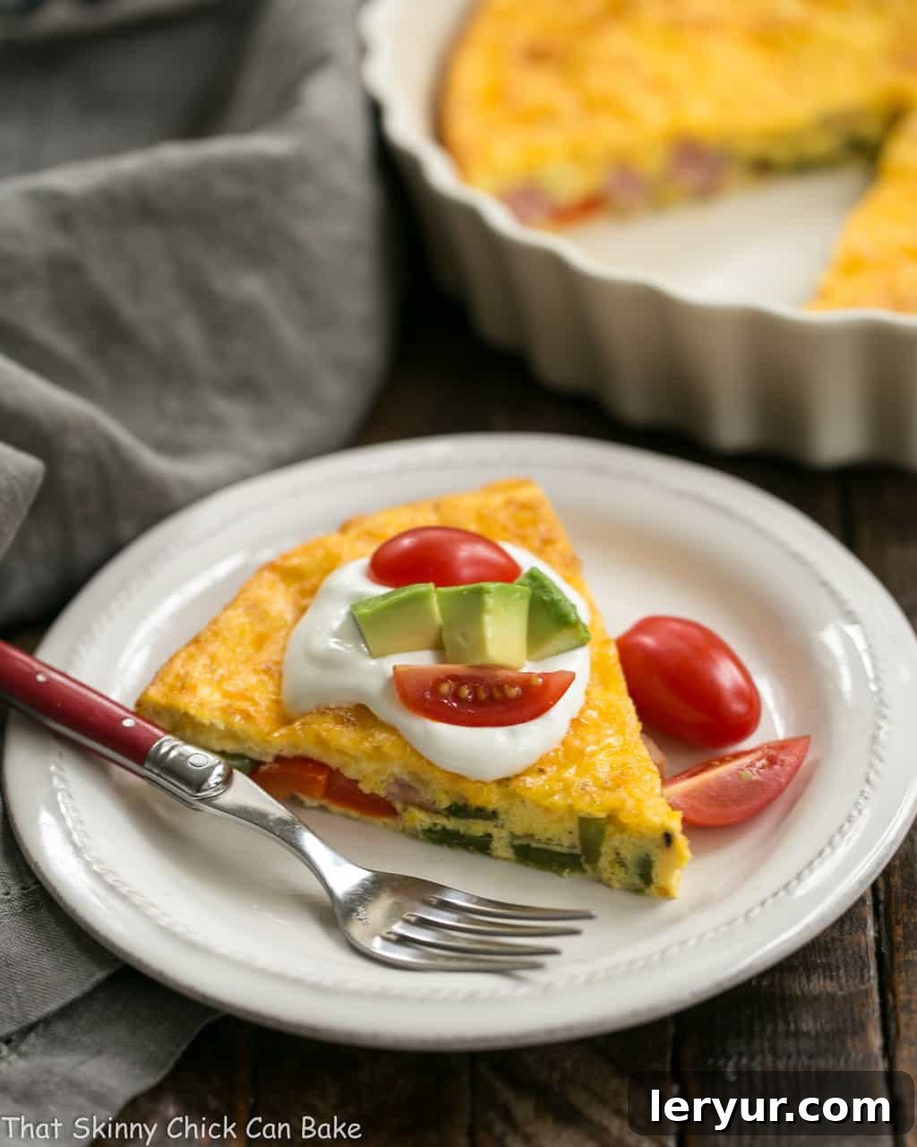 Baked Denver Omelet - A simple, scrumptious, easy to make baked ham and vegetable omelet! Baked Denver Omelet slice on a white plate with the casserole dish in the background.