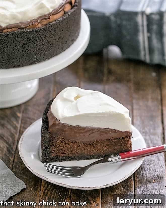 A beautiful slice of Mississippi Mud Pie in the foreground, with the full pie on a stand in the background.