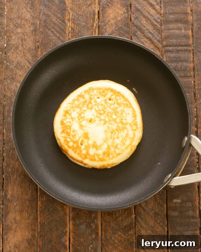 Yaban Mersinli Akçaağaç Şuruplu Ayranlı Pankekler 9 Pancakes cooking on a lightly greased skillet.