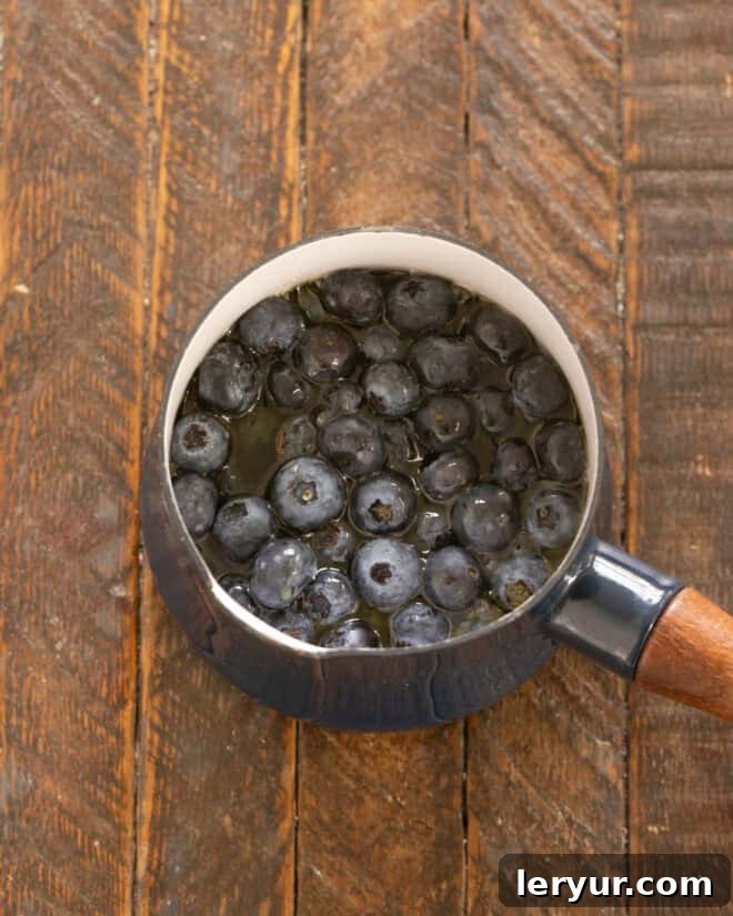 Yaban Mersinli Akçaağaç Şuruplu Ayranlı Pankekler 10 Blueberries and maple syrup simmering in a saucepan.