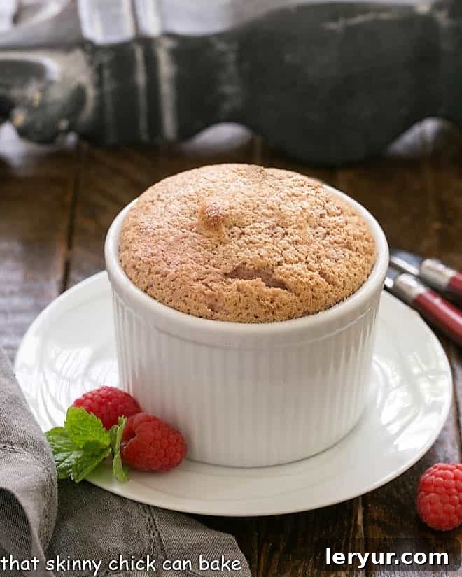 Delightful Individual Raspberry Souffles, elegantly presented on a white plate with fresh raspberry garnish, ready to impress.