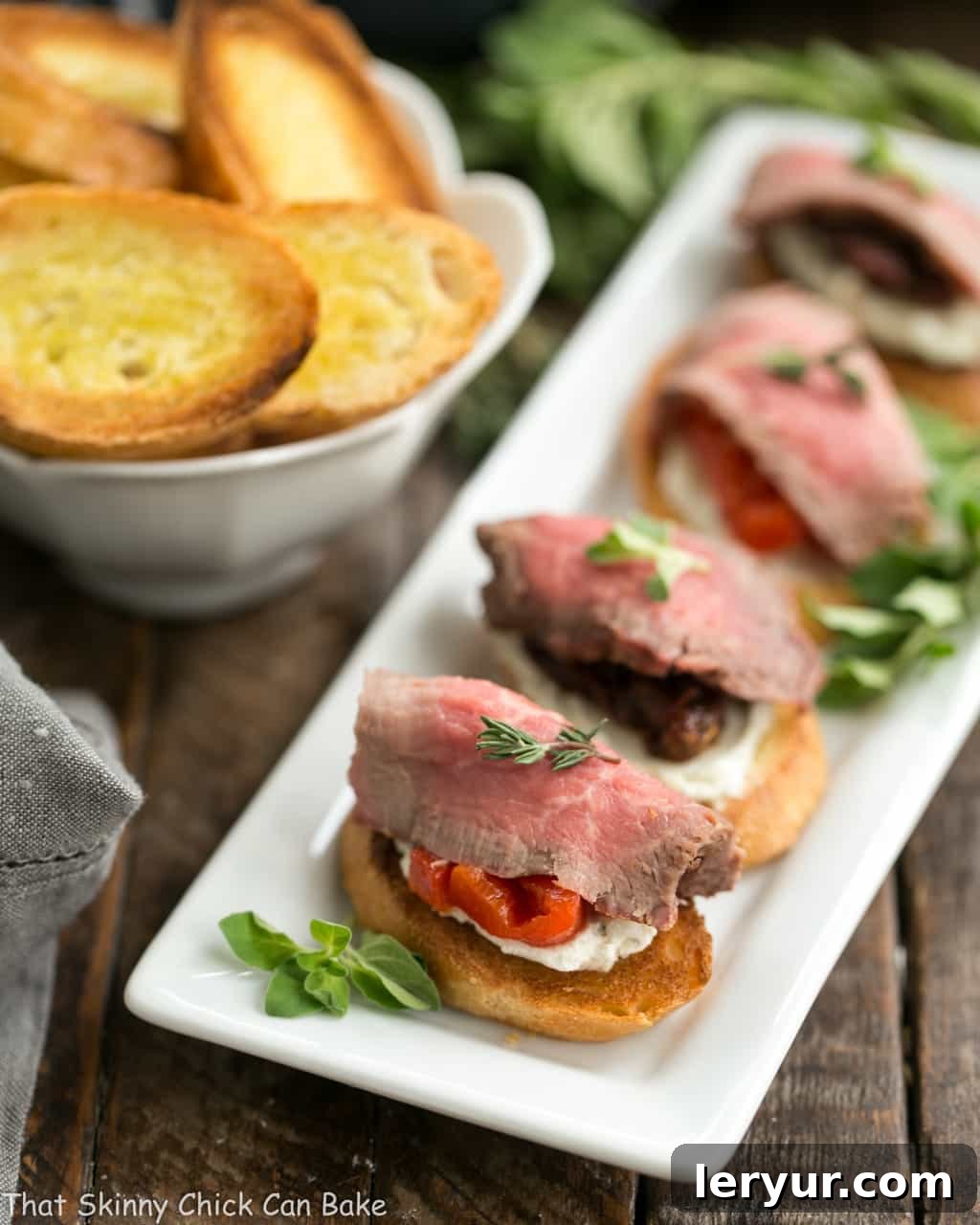 Beef Crostini with Blue Cheese Spread lined up on a white platter.