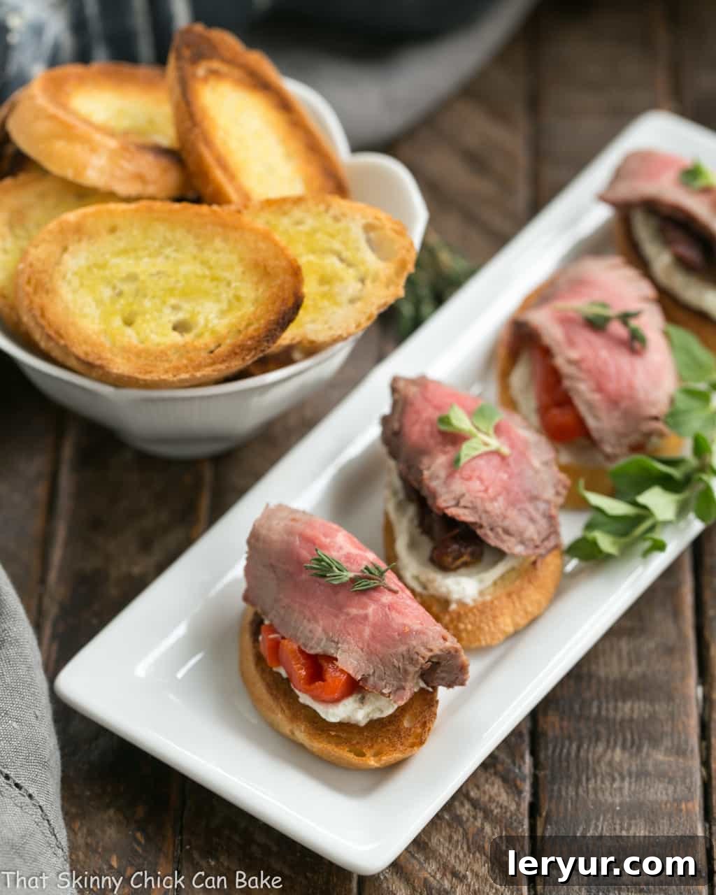Beef Crostini with Blue Cheese Spread on a narrow white tray viewed from above.
