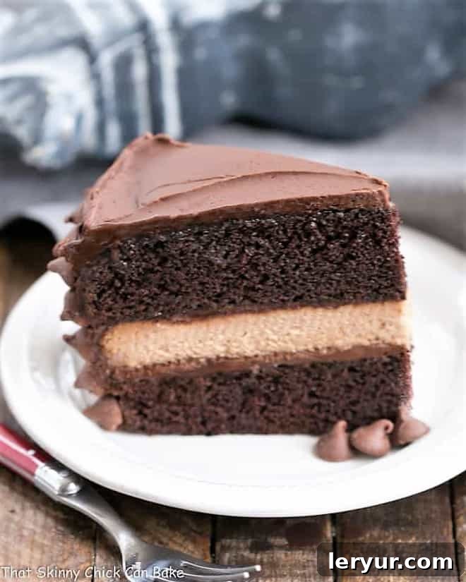 A glorious slice of rich chocolate layer cake, revealing a luscious filling of smooth milk chocolate cheesecake.