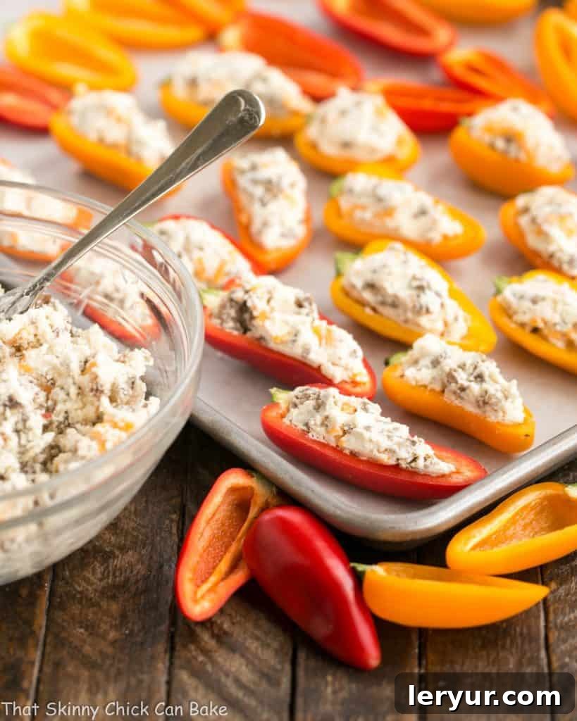 Preparing Cream Cheese Stuffed Mini Peppers: A tray of unstuffed peppers ready for baking, showcasing the ease of assembly for this irresistible appetizer. Unbaked Cream Cheese Stuffed Mini Peppers with Sausage neatly arranged on a parchment-lined baking sheet, ready for the oven.