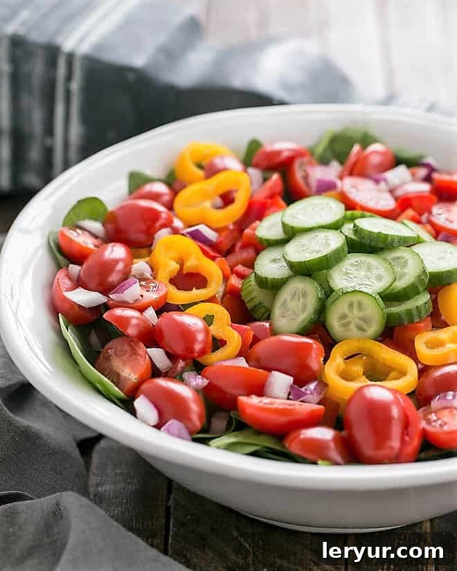 Gazpacho Spinach Salad - a refreshing vegetable salad with a piquant red wine vinaigrette Undressed Gazpacho Spinach Salad in a white ceramic serving bowl.