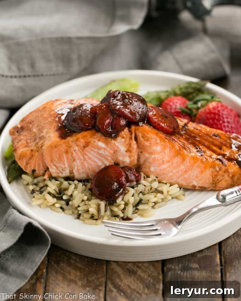 Strawberry Glazed Salmon - Roasted salmon brushed with a tasty, multifaceted strawberry sauce! Strawberry Glazed Salmon on a white dinner plate with rice and fresh strawberries