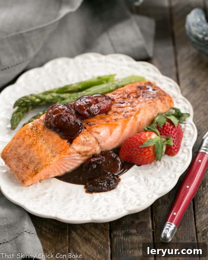 Strawberry Glazed Salmon - Roasted salmon brushed with a tasty, multifaceted strawberry sauce! Strawberry Glazed Salmon on a dinner plate with asparagus and fresh strawberries