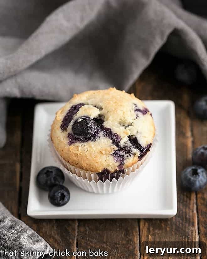 Blueberry Sour Cream Muffins on a white square plate with fresh blueberries