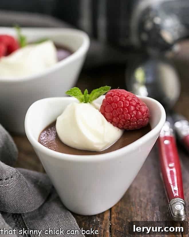 Chocolate Pots de Creme topped with white chocolate cream and raspberries in white ramekins.