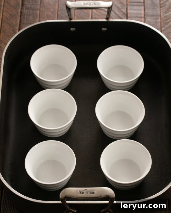 Preheating oven and placing ramekins in a baking dish.