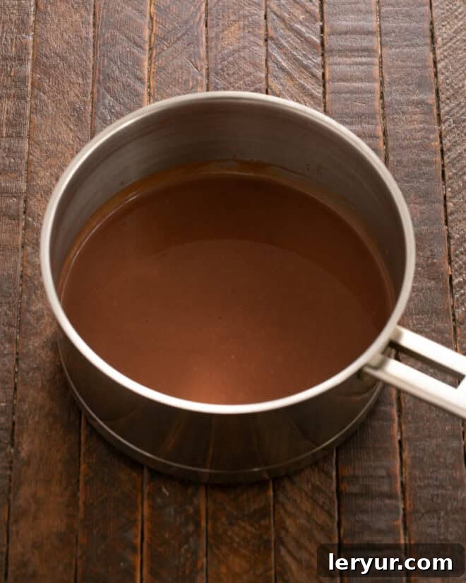 Adding chopped chocolate to hot cream and stirring until melted.