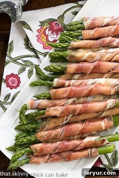 An overhead shot of a white platter filled with perfectly arranged Prosciutto Wrapped Asparagus with Boursin, showcasing their elegant presentation.