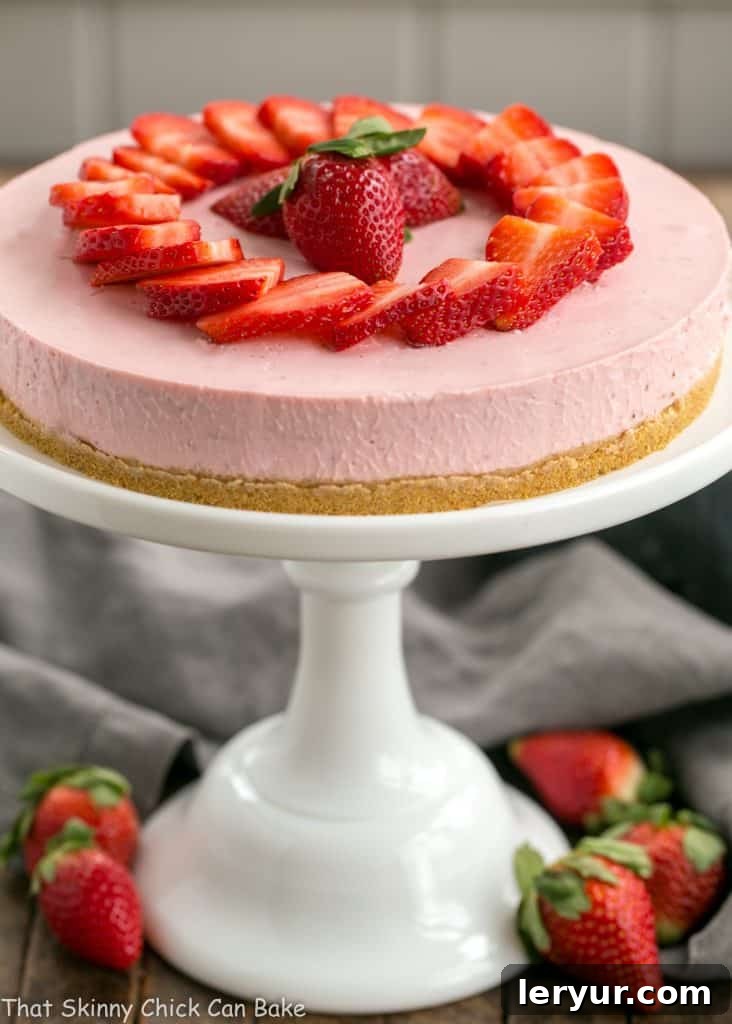 A stunning No-Bake Strawberry Cheesecake presented on a pristine white ceramic cake stand, ready to be enjoyed.