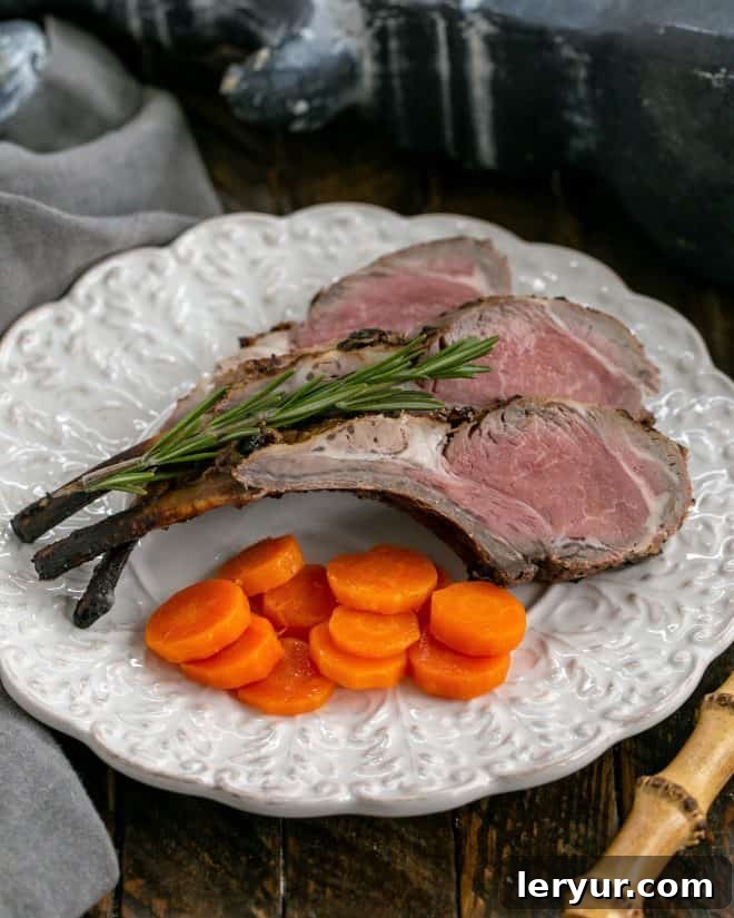 Grilled Lamb Chops Infused with Rosemary, Garlic, and Tangy Mustard 2 Overhead view of lamb chops on a white decorative plate with a sprig of rosemary and carrot coins