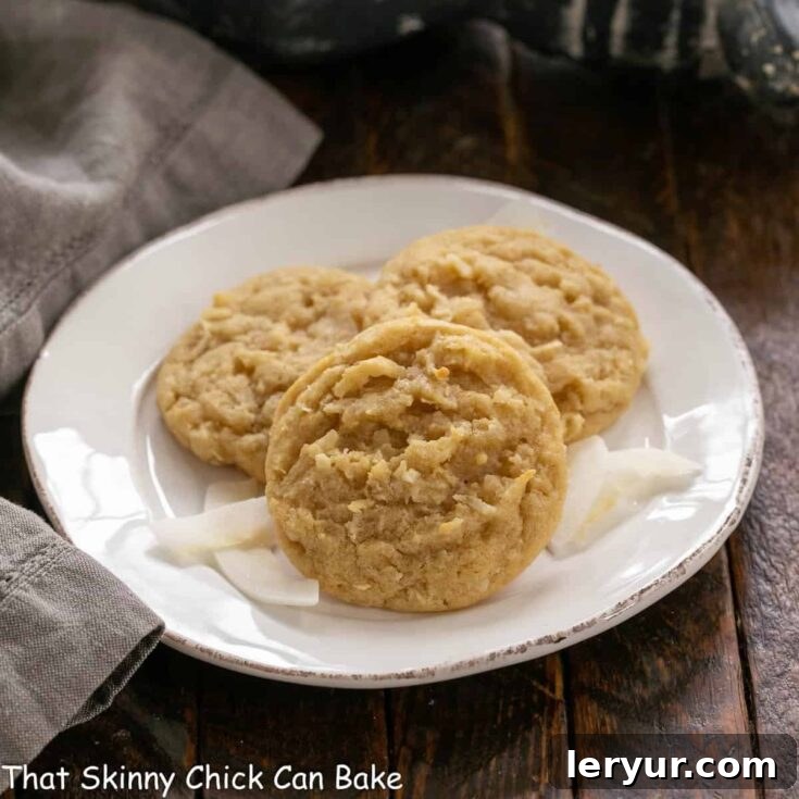 3 chewy coconut cookies artfully arranged on a white ceramic plate, ready to be enjoyed.