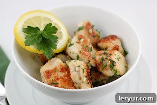 Close-up of golden brown chicken with fresh green parsley garnish in a skillet